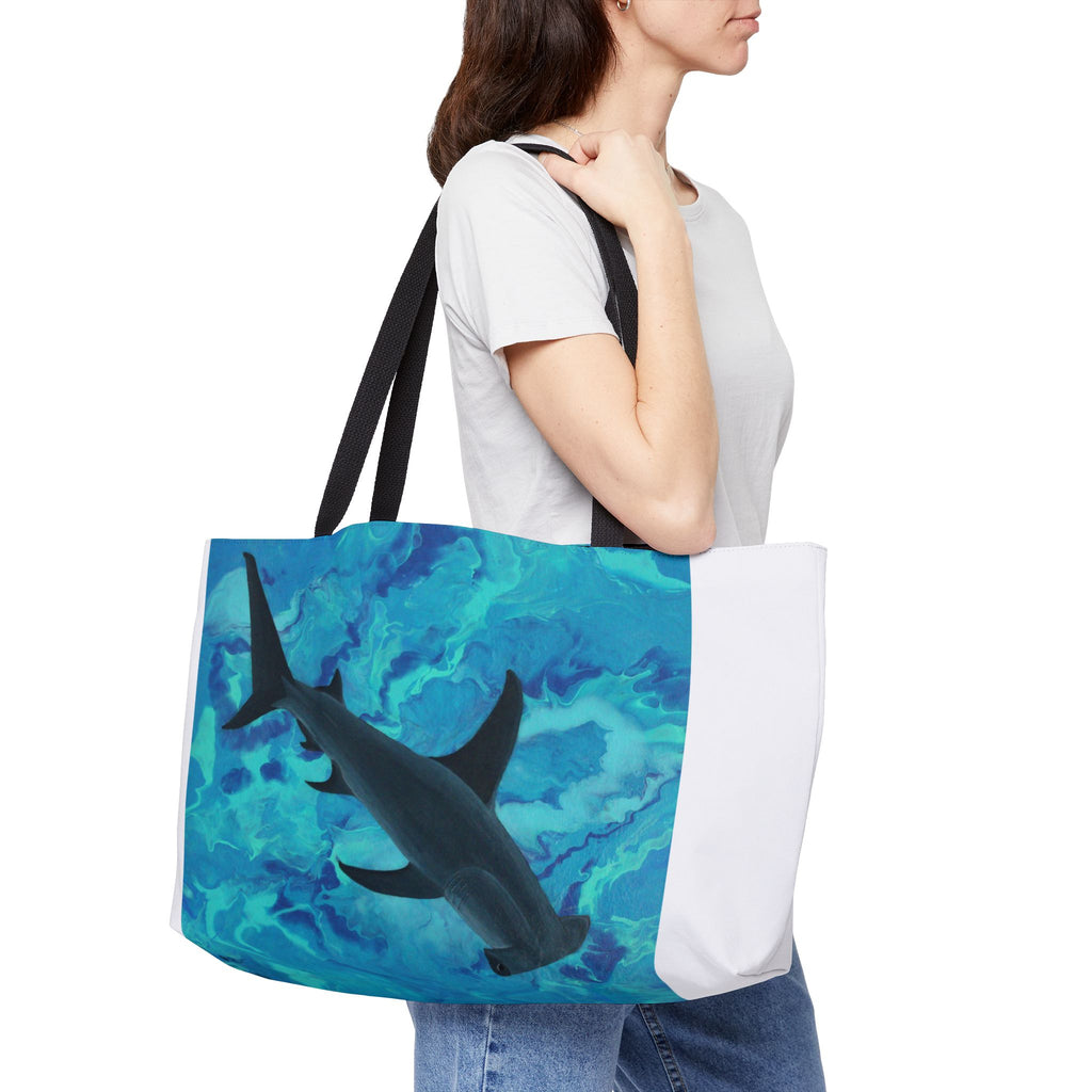 Person holding a tote bag with a shark design on a white background