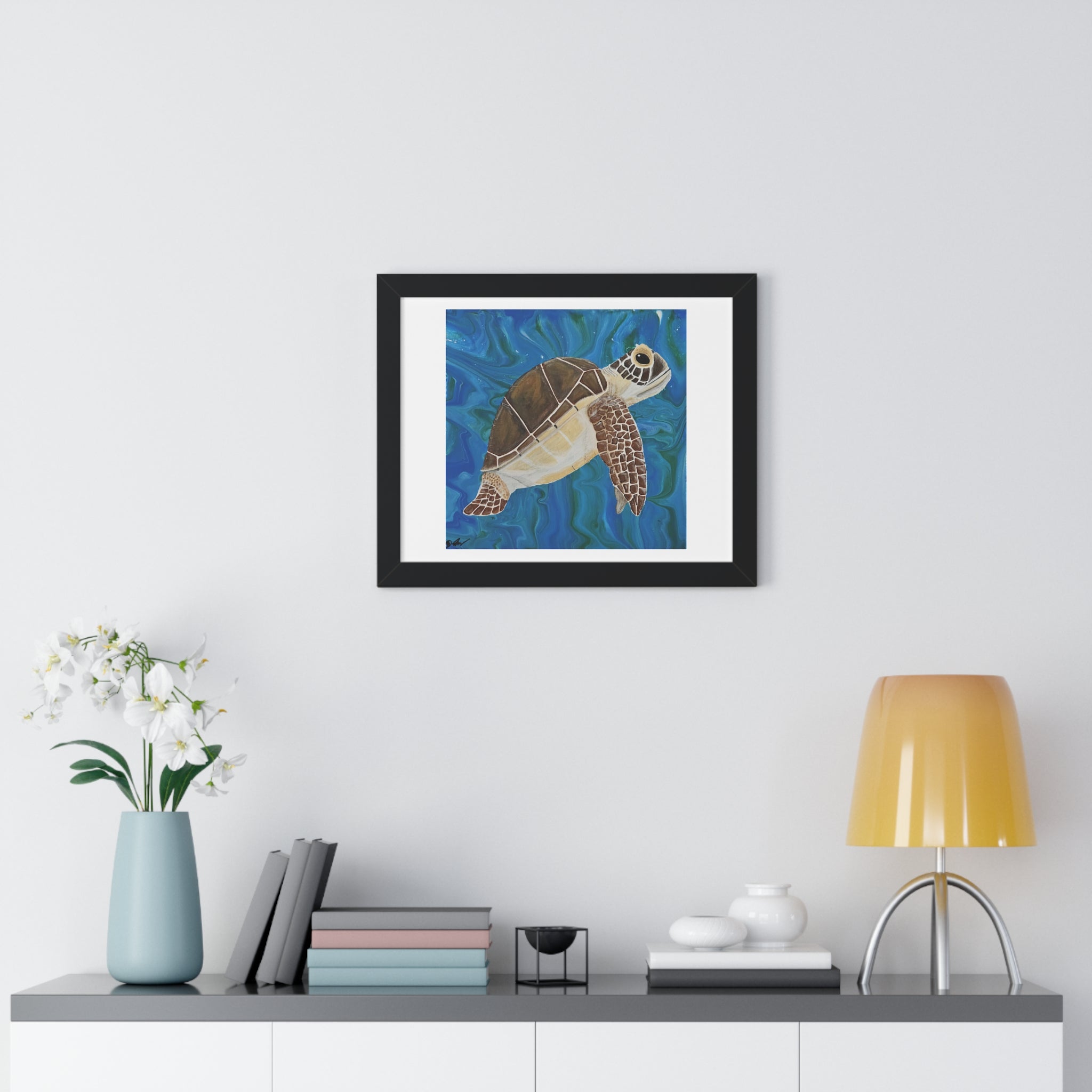 Framed artwork of a turtle on a wall above a shelf with decor items.