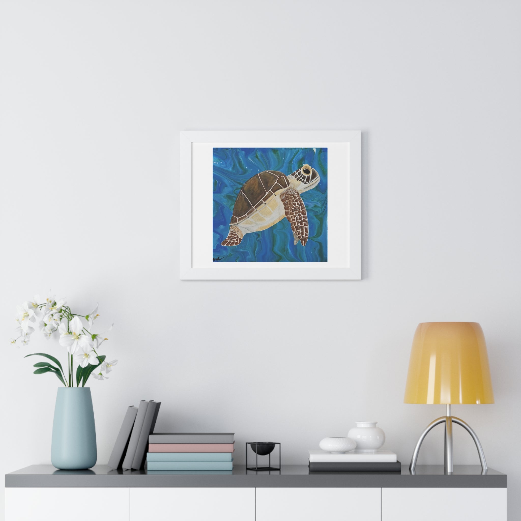 Framed artwork of an alien head on a wall above a desk with decor items.