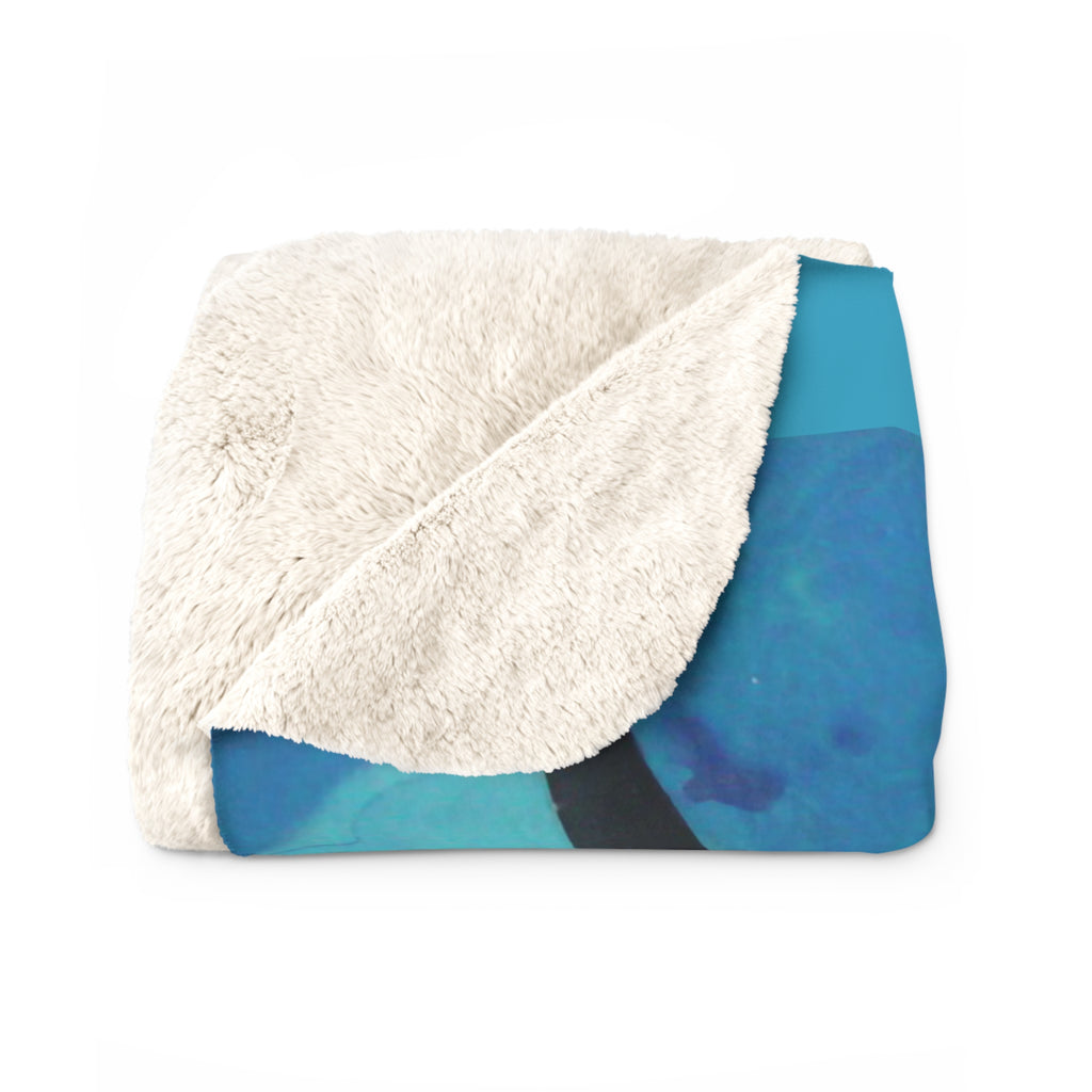 Folded blanket with white sherpa interior and blue abstract pattern exterior on a white background