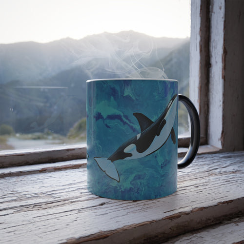 Mug with an orca design on a windowsill with a mountain view